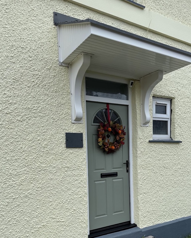 Sage-green front door freshly painted beneath a white porch canopy