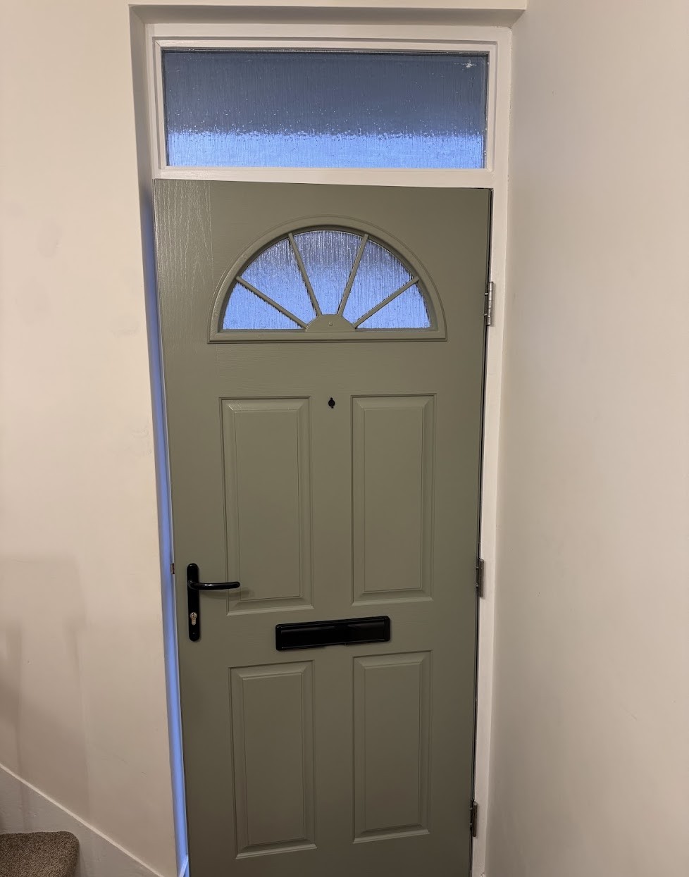 Sage-green interior front door with a glazed fanlight and freshly painted white trim
